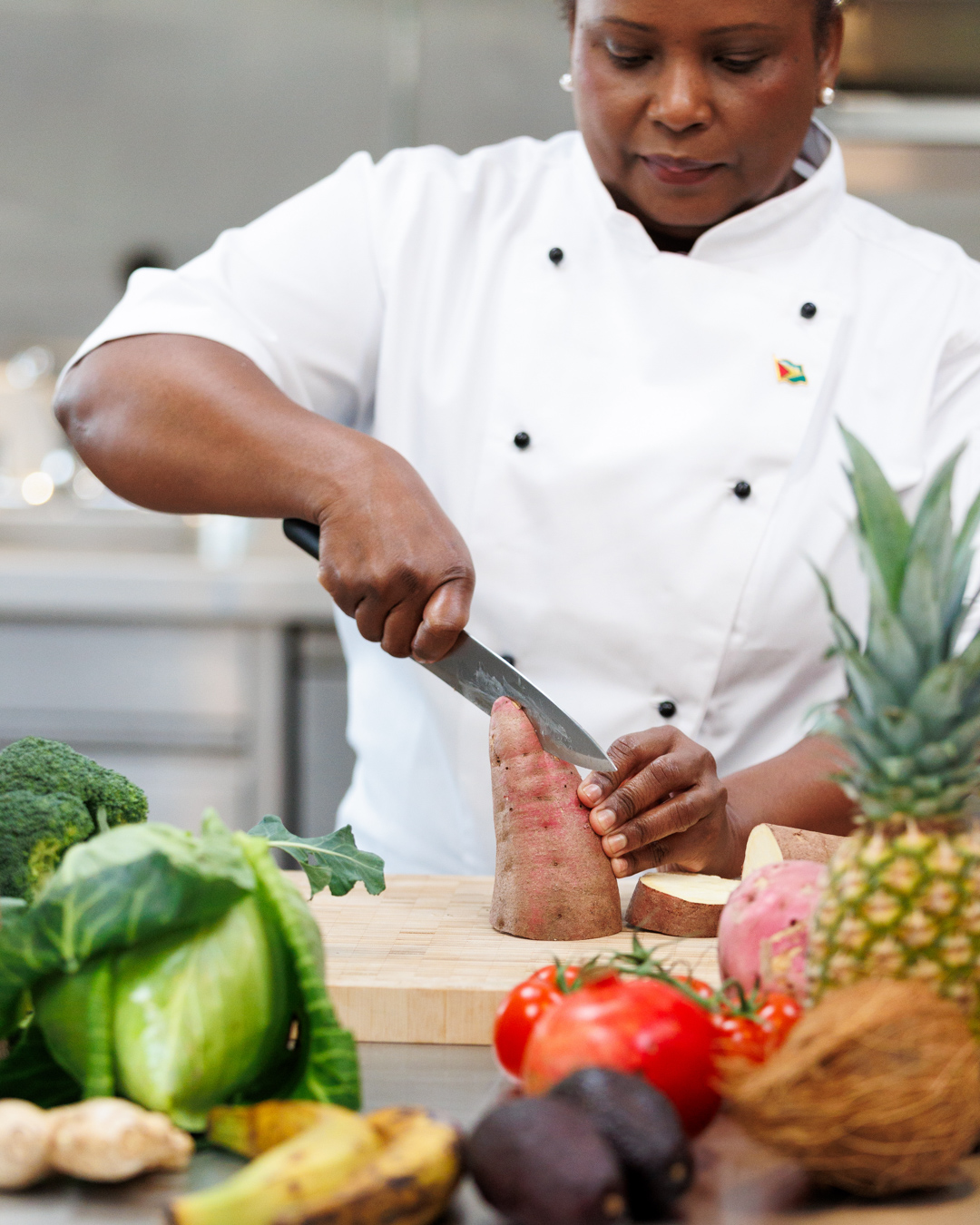 Mahalia in chef whites preparing Caribbean produce